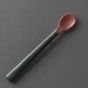 Tommee Tippee Heat Sense Weaning Spoon in red and black, featuring a textured handle for better grip.