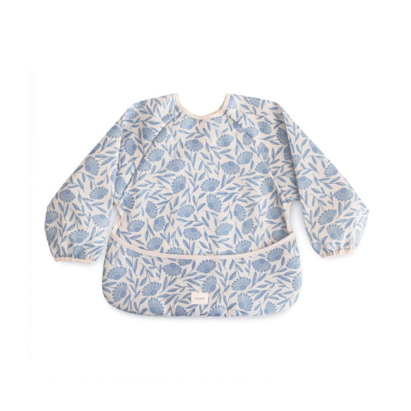 Mushie Long Sleeve Bib in blue flowers design, featuring elastic cuffs and a front pocket for easy cleanup.