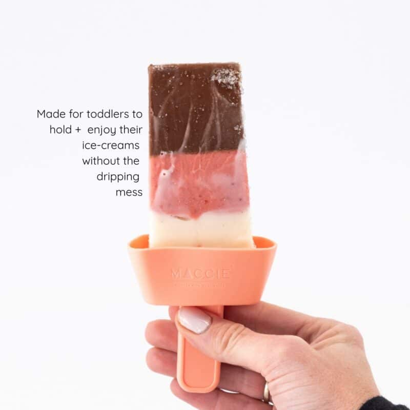 Maccie jolly lolly holder in pink, designed for toddlers to enjoy ice creams without mess, held in a hand.