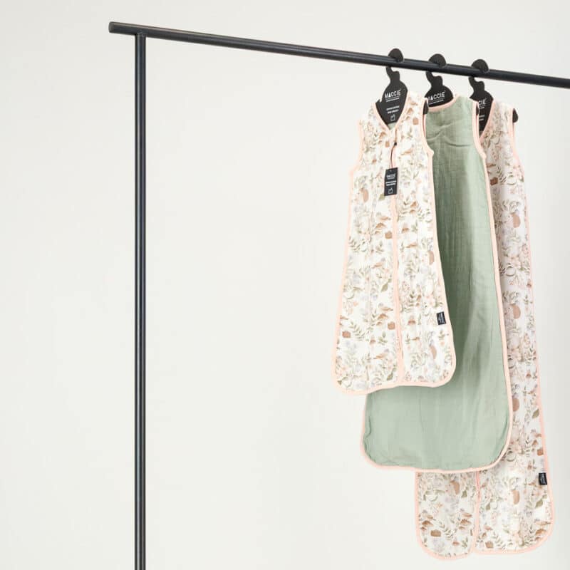 Maccie Summer Sleep Sac for 3-9 months in floral and sage green, hanging on a display rack.