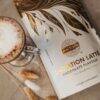 Made to Lactate Lactation Chocolate Latté package beside a glass of latte, featuring a stylish design with gold accents.