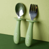 Junary Little Bites Cutlery Duo in green, featuring a spoon and fork with ergonomic handles for easy grip.