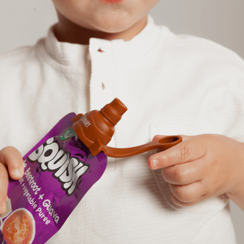 Junary Tiny Toppers Duo in use, featuring a child holding a pouch with a brown silicone topper for easy feeding.