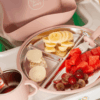Junary Little Gripper Starter Kit in pink with a divided plate holding banana slices, watermelon, grapes, and cookies.