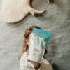 Made to Lactate Lactation Vanilla Latté in a stylish bag held by a woman, set against a rustic wall backdrop.