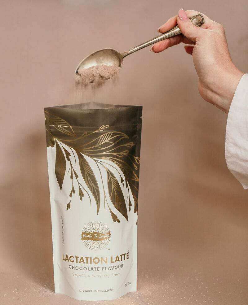 Made to Lactate Lactation Chocolate Latté in a gold and white pouch, with a hand pouring powder using a spoon.