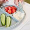 b.box silicone plate in Ocean with three compartments, featuring strawberries, cucumber slices, and yogurt.