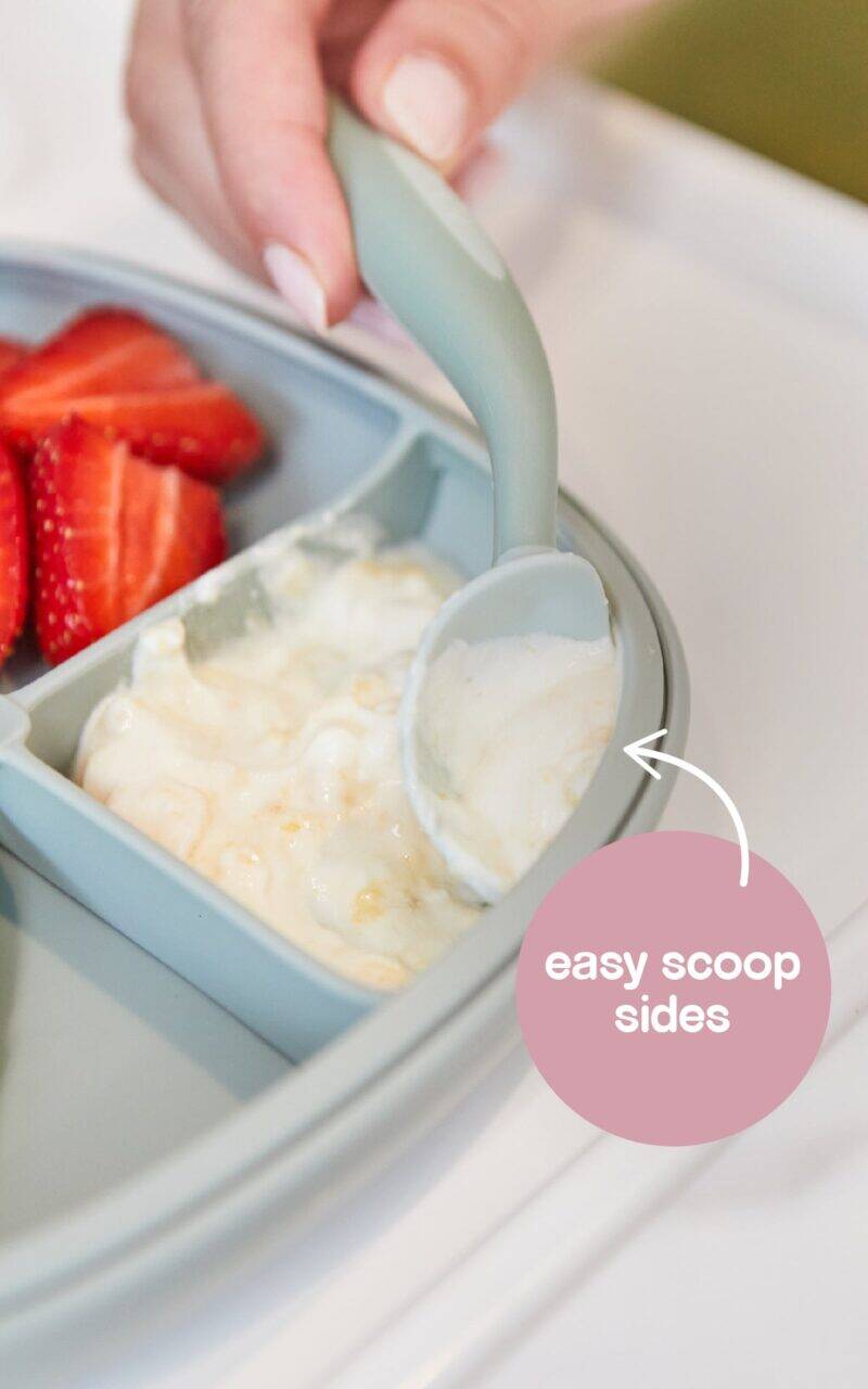 b.box silicone plate in blush with easy scoop sides, featuring a green spoon and strawberries on the side.