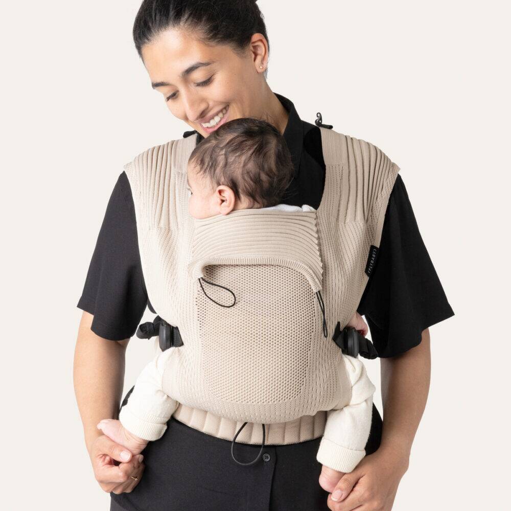 Flybaby Baby Carrier in Creme, featuring a textured design, worn by a parent with a baby comfortably secured.