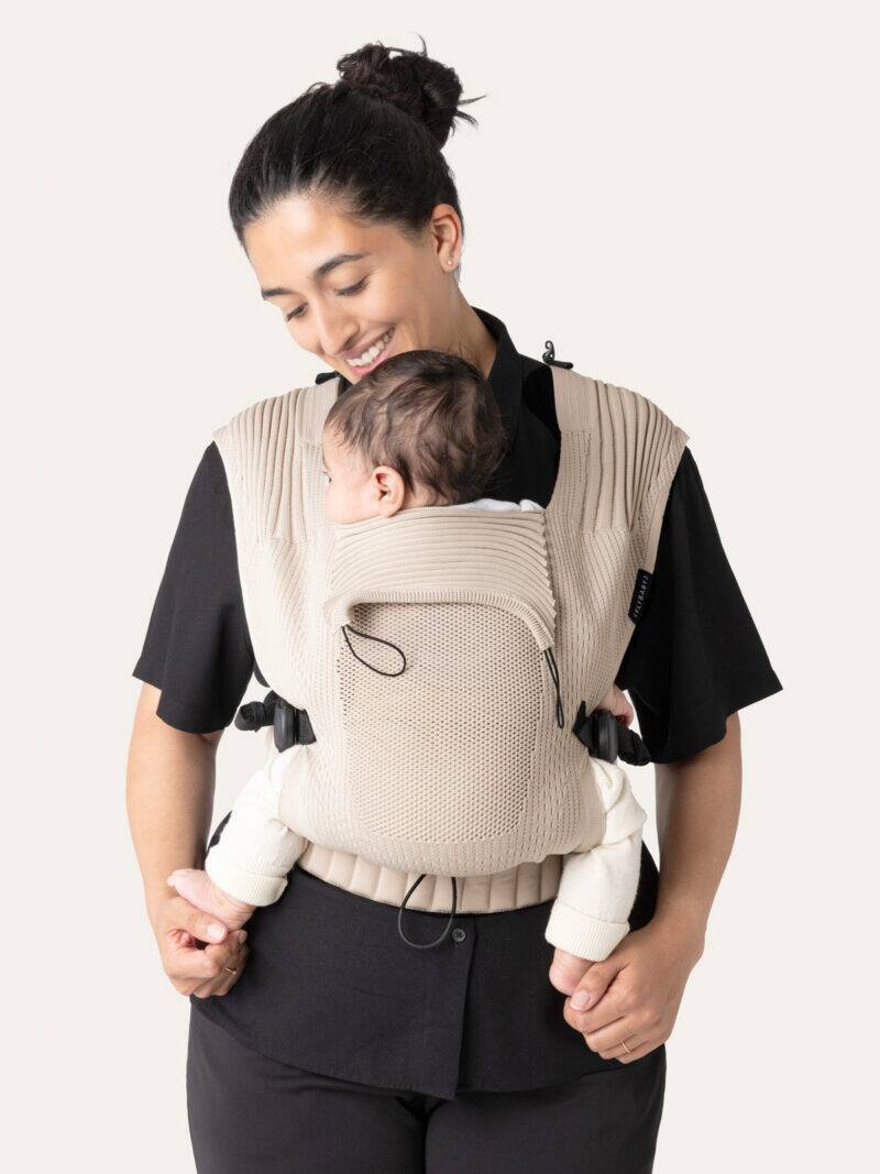 Flybaby Baby Carrier in Creme, featuring a textured design, worn by a parent with a baby comfortably secured.