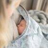 Baby Sense denim nursing cover draped over a mother, cradling a peacefully sleeping baby inside.