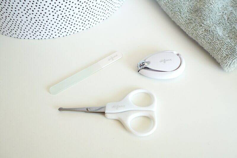 Difrax deluxe manicure set featuring a nail clipper, scissors, and nail file on a light surface with a towel in background.