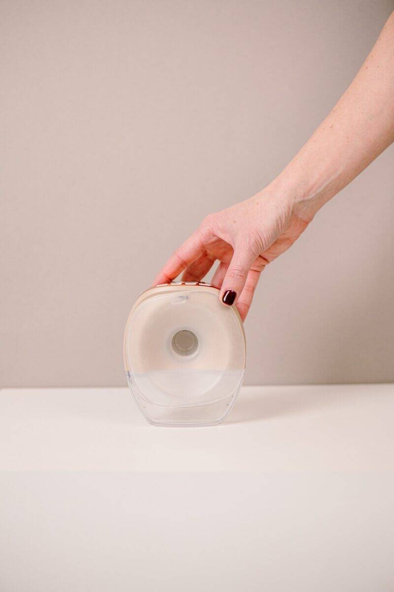 Difrax Handsfree Breastpump with a clear design, held by a hand, showcasing its ergonomic shape and functionality.
