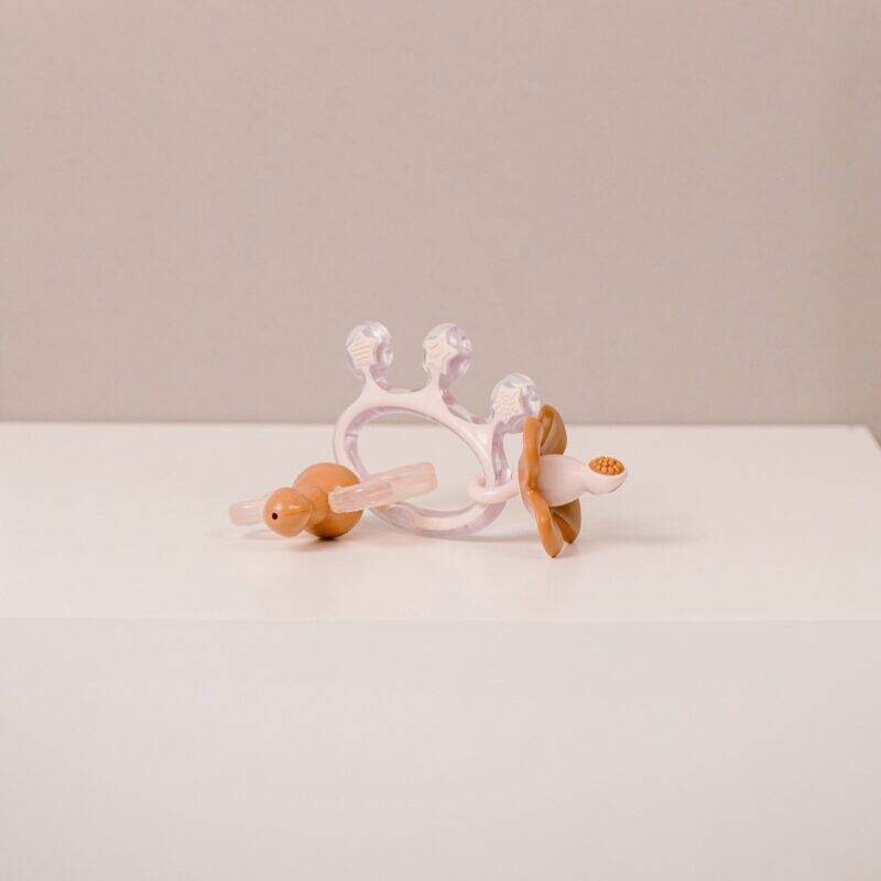 Difrax Crown Teething Ring in pink and wood, featuring a crown design and textured surfaces for soothing gums.