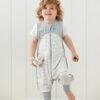 Love to Dream Swaddle Up Sleep Suit 0.2 TOG in Daydream Grey, featuring cloud patterns, worn by a smiling toddler.