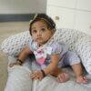 Snuggletime 2-in-1 Teether Bandana Bib in butterfly print worn by a baby sitting on a soft, patterned play mat.