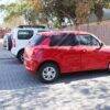 Snuggletime Curved Window Shades on a red car parked in a sunny lot, providing shade and privacy for the vehicle.