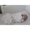 Snuggletime Bamboo Muslin Receiver in Pink Llama design, gently wrapped around a sleeping baby in a crib.