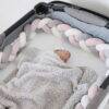 Snuggletime Braided Cot Bumper in blue, grey, and pink, featuring a cozy sleeping baby wrapped in a fluffy blanket.