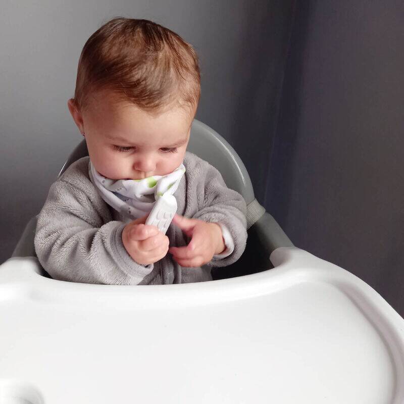 Snuggletime 2-in-1 Teether Bandana Bib in butterfly design, worn by a baby in a high chair, focusing on teething feature.
