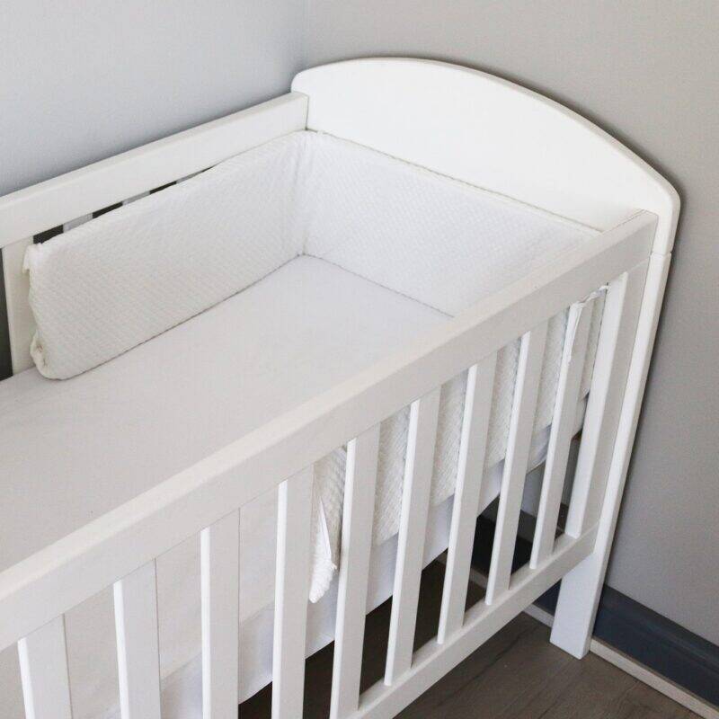 Snuggletime Bamboopaedic Cot Bumper and Cover in white, fitted snugly inside a white cot with a minimalist design.