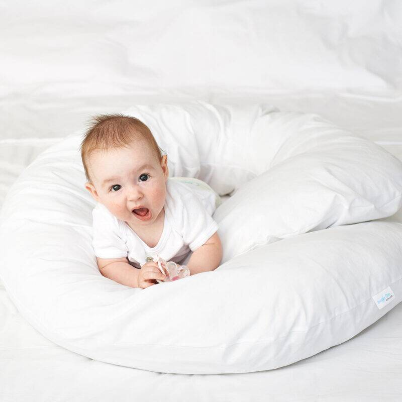 Snuggletime Body Comfort Pillow in white with a baby happily playing on it, showcasing its soft and supportive design.