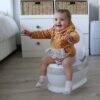 Snuggletime Comfort Toilet Seat Potty in white, featuring a smiling toddler wearing a cozy orange polka dot hoodie.
