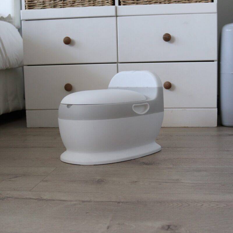 Snuggletime Comfort Toilet Seat Potty in white and grey, designed for toddlers, placed on a wooden floor in a cozy room