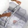 Snuggletime Dome Mosquito Protection Netting in grey, securely covering a baby in a portable crib, ensuring insect safety.