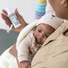 BabySafe Pacifier Cleaner & Sanitiser in hand, with a baby wrapped in a blanket, surrounded by colorful stacking toys.