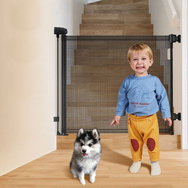 Snuggletime Autolock Retractable Safety Gate in black and gray, installed at stairs with a child and a small dog nearby.