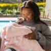 Snuggletime Double Fleece Baby Blanket in pink with white stars, cozy setting outdoors with a woman holding a baby.