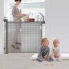 Snuggletime Autolock Retractable Safety Gate in black and gray, shown in a home setting with children playing nearby.