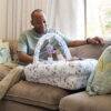 Snuggletime Deluxe Comfort Pod with Activity Arch, featuring a parent playing with a baby, set on a cozy couch.