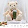 Aromababy Healing Balm tube displayed with a soft teddy bear against a white towel backdrop, highlighting its soothing