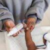 Aromababy baby oil held by a caregiver, gently applying it to a baby's arm during a bath time setting.