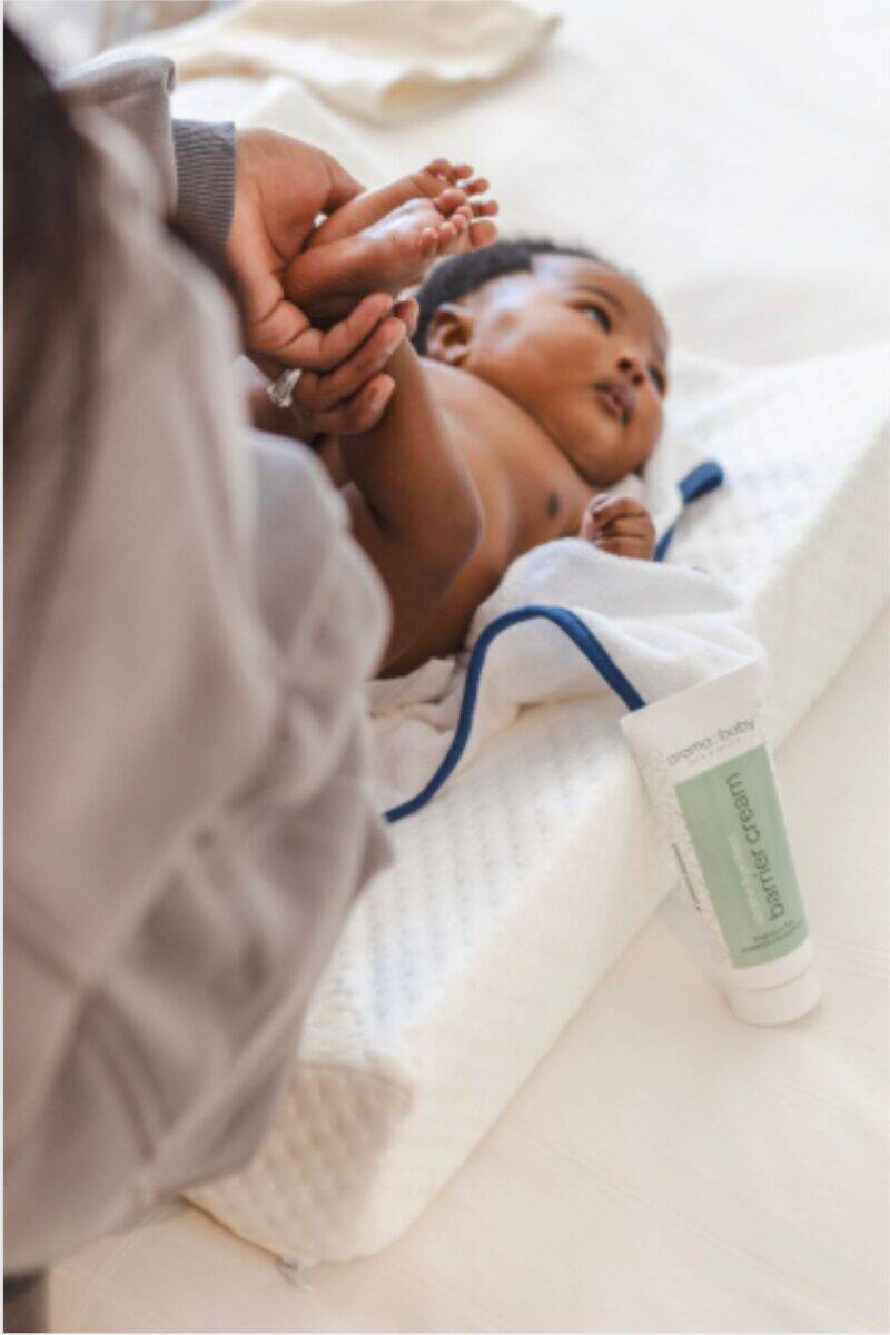 Aromababy Barrier Cream displayed next to a baby being cared for, highlighting gentle skin protection in a cozy setting.