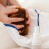 Aromababy Cradle Cap spray in a white bottle, with a person gently massaging a baby's head on a soft blanket.