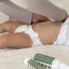 Aromababy Healing Balm and Baby Lotion displayed beside a baby lying on a soft blanket, emphasizing gentle skincare.