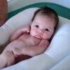 Snuggletime Microbead Baby Bather Cushion in blue and white, cradling a baby comfortably in a bath setting.