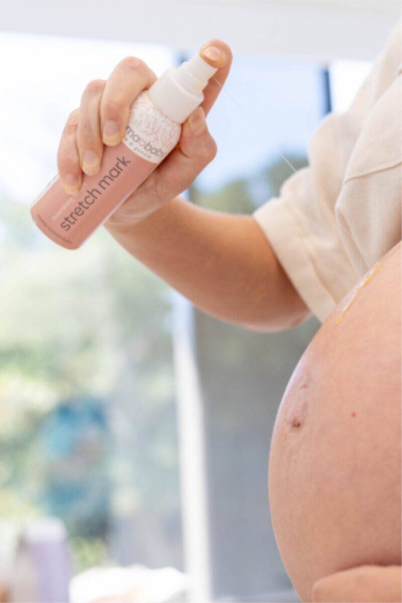 Aromababy stretch mark spray being applied to a pregnant belly, showcasing a nurturing skincare routine for moms-to-be.