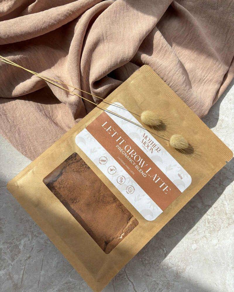 Mother Nature's Let It Grow Latte, a brown powder blend in a kraft pouch, placed on a soft, beige fabric backdrop.
