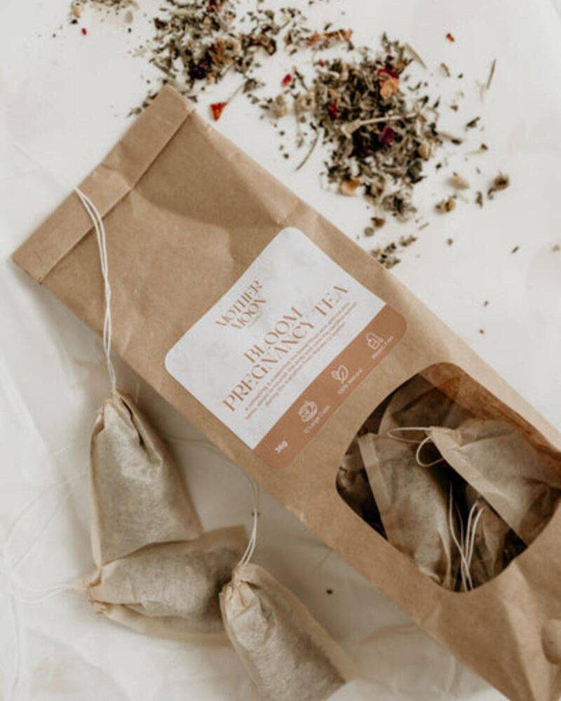 Lorna Jane Body Pregnancy Tea in eco-friendly packaging with three tea bags and loose herbal blend scattered around.