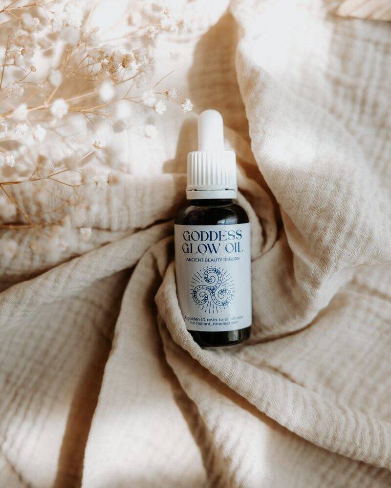 Goddess Glow Oil by Lorna Jane, a beauty oil in a dropper bottle, placed on soft beige fabric with dried flowers.